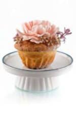 Sweet floral cupcake with pink flower decoration on a white cake stand.