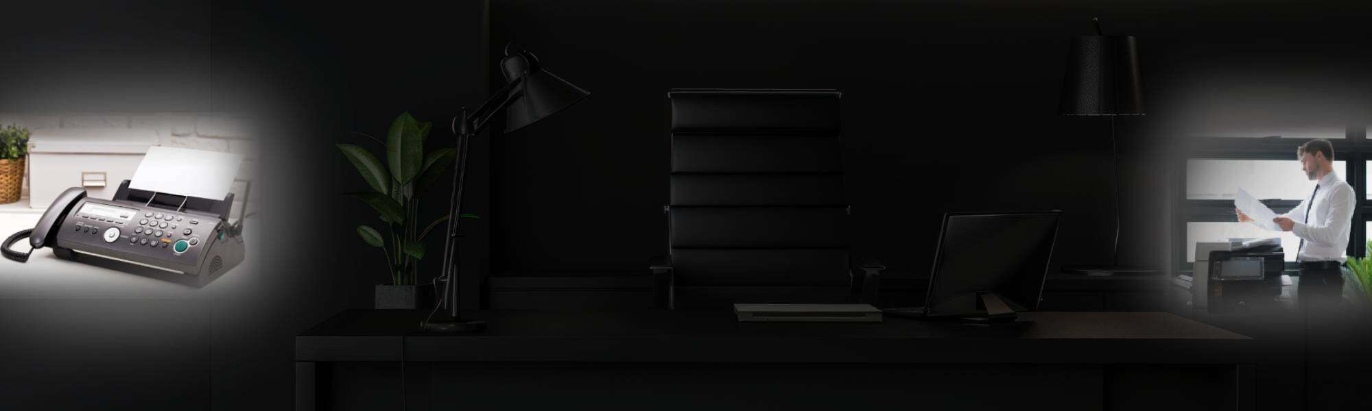 Office desk with computer, lamp, and plant in a sleek, professional environment.